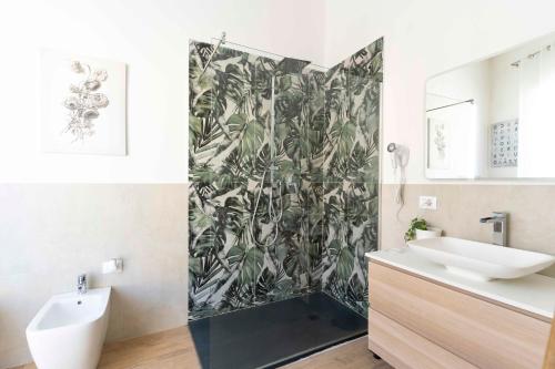 a bathroom with a sink and a shower with a tropical wallpaper at Montecristo B&B in Grosseto