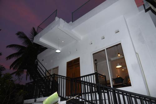 uma casa branca com uma escada e uma palmeira em Everdew Kandy em Kandy