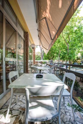 an outdoor patio with tables and chairs and windows at Hotel Tiziana in Rimini