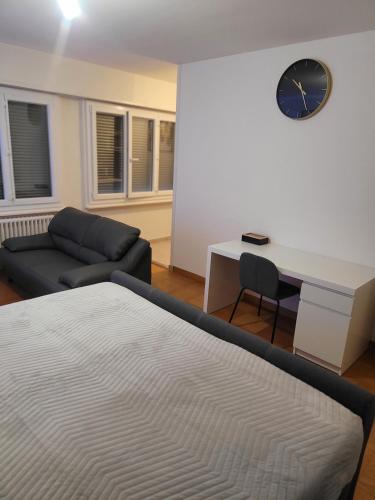 una camera con letto, scrivania e orologio di Studio meublé a Ginevra