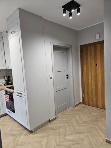 a kitchen with white cabinets and a wooden floor at Apartament Konstancji in Piła