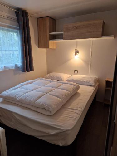 un grand lit dans une chambre avec une fenêtre dans l'établissement Mobil home tout confort 3 chambres camping Les Pierres Couchées, à Saint-Brévin-les-Pins