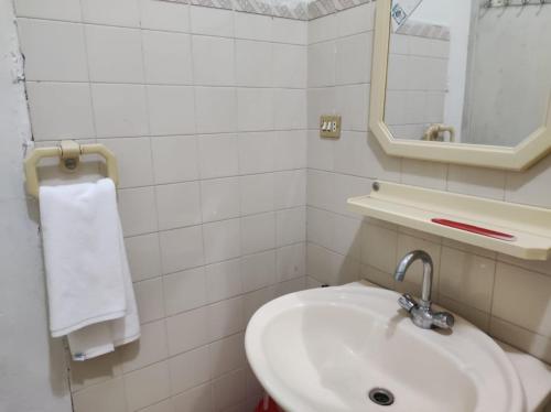 a white bathroom with a sink and a mirror at Askari Gold Crest in Peshawar