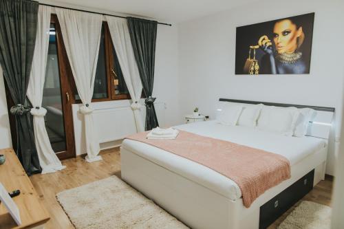 a bedroom with a large white bed with a painting on the wall at Alessandra-Aparthotel in Piatra Neamţ