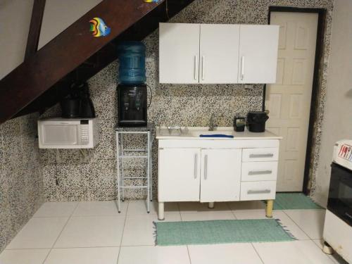 a kitchen with white cabinets and a microwave at Village Gales Prive Maragogi in Maragogi