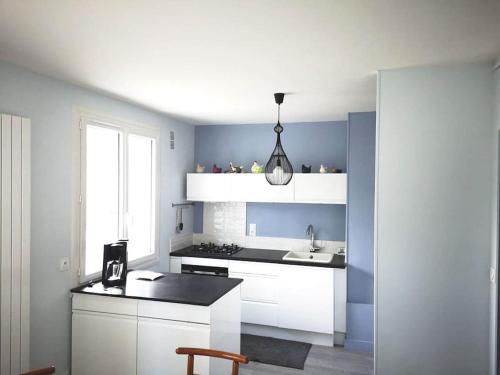 une cuisine avec des armoires blanches et un évier dans l'établissement Tout le charme de La Baule-Les -Pins T3 73m2, à La Baule