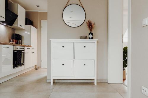 einen weißen Schrank in einer Küche mit Spiegel in der Unterkunft WohnungTraveller Geislautern in Völklingen