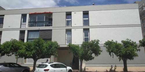 un bâtiment blanc avec des voitures garées devant lui dans l'établissement Grand studio cabine à 100 m plage et commerces, à Saint Cyprien Plage