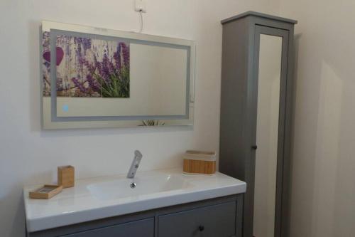 La salle de bains est pourvue d'un lavabo et d'un miroir. dans l'établissement Jolie Maison avec jardin et piscine privée, à Sablet