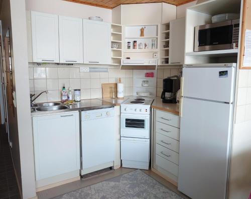 a kitchen with white appliances and white cabinets at Rivitalon lomahuoneisto Tahkolla in Tahkovuori