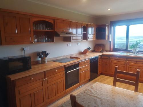 a kitchen with wooden cabinets and a large window at Taigh Mairi Grimsay in Carinish