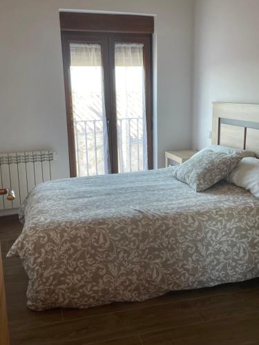 a bedroom with a bed with a blanket and two windows at Casa Capricho in Horcajo de las Torres