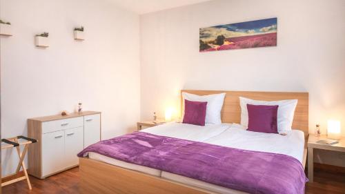 1 dormitorio con 1 cama grande con sábanas moradas en Gemütliches Nest mit Garten in der Heide, 