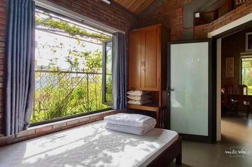 Homestay Mộc Nhi في هوى: غرفة مع نافذة كبيرة وسرير في غرفة