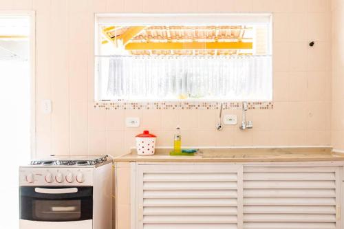 a kitchen with a stove and a sink and a window at Casa Aconchego - O refúgio perfeito para amar e descansar in Peruíbe