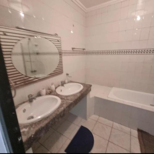 ein Badezimmer mit zwei Waschbecken, einer Badewanne und einem Spiegel in der Unterkunft Appartement centre Agadir in Agadir