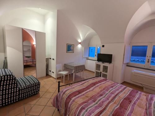 een slaapkamer met een bed, een stoel en een televisie bij Méditerranée in Minori
