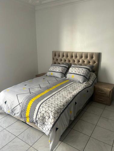 Schlafzimmer mit einem Bett mit einem gepolsterten Kopfteil in der Unterkunft Appartement centre Agadir in Agadir