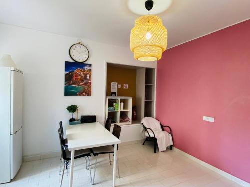 a dining room with a white table and a pink wall at Central Atlantic Beach Guesthouse in Costa da Caparica
