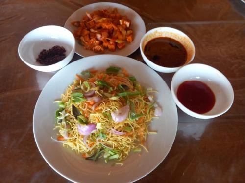 a table with a plate of food and bowls of sauce at Thisha Hotel & Restaurant in Jaffna