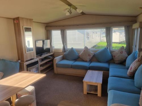 sala de estar con sofá azul y TV en Newquay Bay Porth Caravan - 6 berth en Newquay