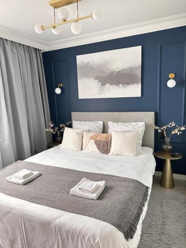a bedroom with a large white bed with blue walls at Apartament ZARA - Widok na morze! in Władysławowo