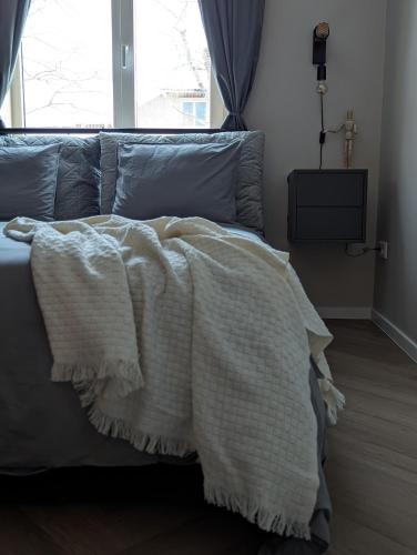 a bed with a white blanket on top of it at Mere Apartment - Private Yard, Sauna and Pet Friendly in Pärnu