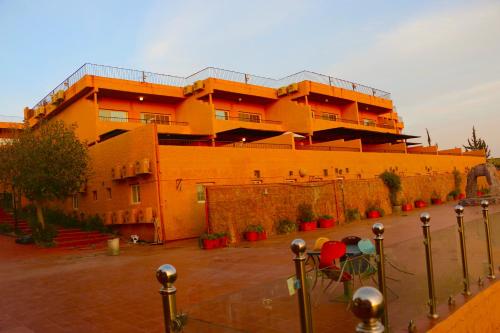 a large orange building with red plants in front of it at منتجع داري الهدا in Al Hada