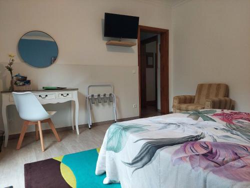 1 dormitorio con cama, escritorio y espejo en Quinta dos Aromas, en Lagoa