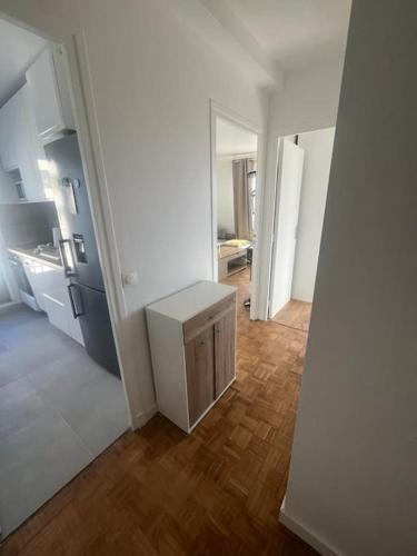 Il comprend une cuisine équipée d'un réfrigérateur blanc et du parquet. dans l'établissement Appartement côté Parc de Sceaux, à Bourg-la-Reine