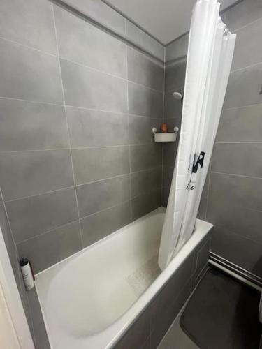 La salle de bains est pourvue d'une baignoire blanche avec rideau de douche. dans l'établissement Appartement côté Parc de Sceaux, à Bourg-la-Reine