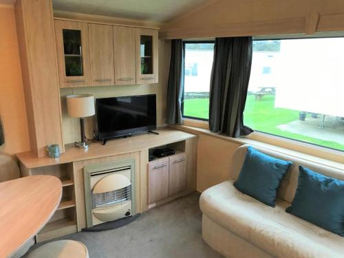 a caravan living room with a tv and a couch at Newquay Bay Porth Caravan - 8 Berth in Newquay