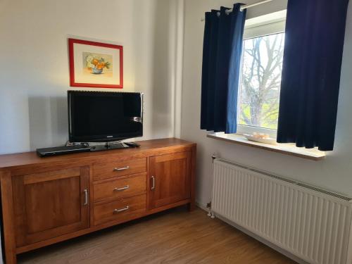a tv on a wooden dresser in a room with a window at Amselpark in Barkelsby