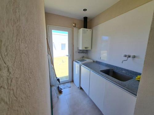 a small kitchen with a sink and a window at Casafresnos Costa Esmeralda Pinamar in Pinamar