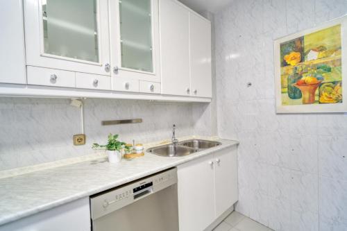a kitchen with white cabinets and a sink at Dúplex en centro, San Ildefonso in Jaén