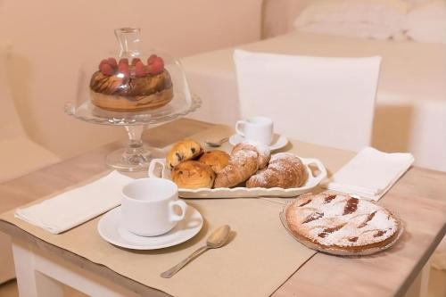 una mesa con una bandeja de bollería y un plato de pan en Dimore di Gio' Luxury Private Wellness Spa en Ostuni