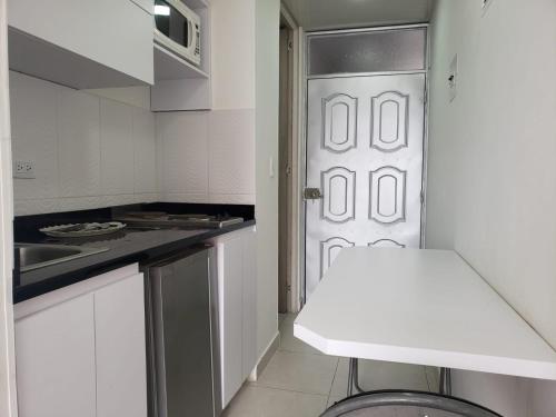 uma cozinha com uma porta branca e um lavatório em Apartahotel Barú - Usaquén em Bogotá