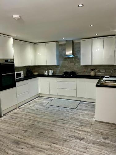 a kitchen with white cabinets and a wooden floor at Swanmore in Derby