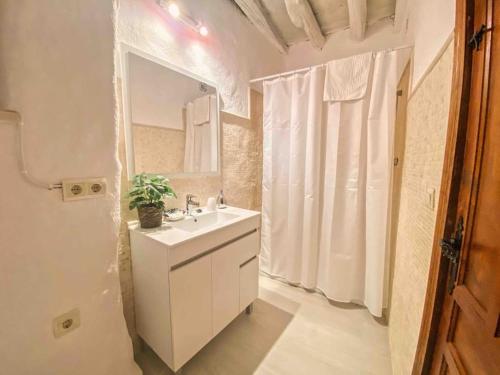een witte badkamer met een wastafel en een spiegel bij La Palmera. Casa rural con piscina privada. in Benadalid