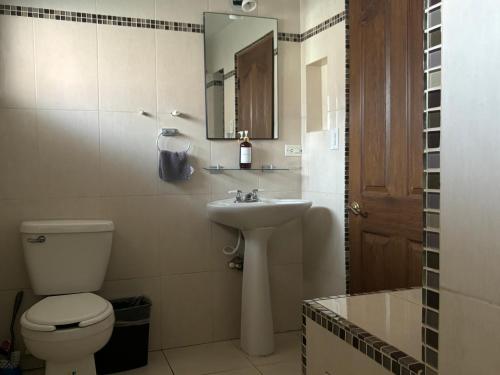 La salle de bains est pourvue de toilettes, d'un lavabo et d'un miroir. dans l'établissement Casa Macfarland Boutique, à Ensenada