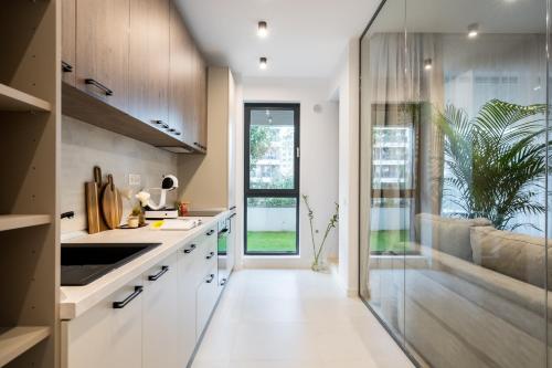 ブカレストにあるBOTANlQUE 1BR in Business Centreの白いキャビネットと大きな窓のあるキッチン