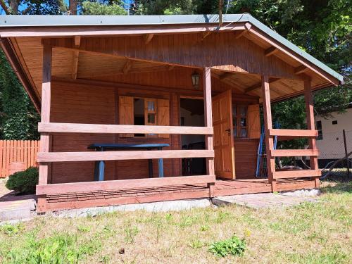 een houten gebouw met een veranda in een veld bij Nadmorska Pieredyszka in Junoszyno