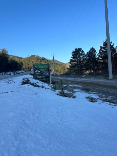 uma estrada coberta de neve com um sinal na lateral da estrada em Bungalow Gölçam em Denizli