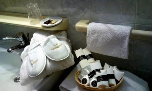 a bathroom with a basket of towels and a sink at Hotel Benaco in Sirmione