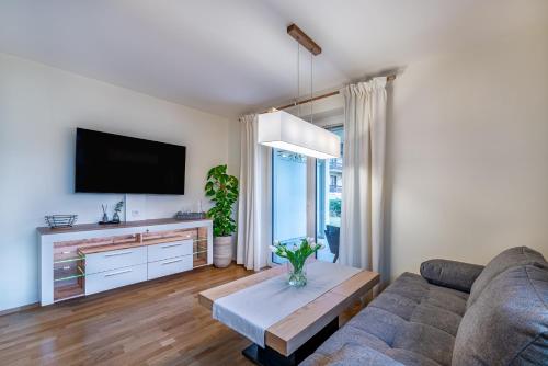 a living room with a couch and a tv at Well-Home Apartments Velden in Velden am Wörthersee