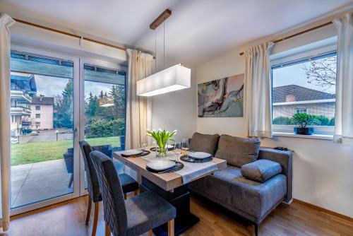 a living room with a dining room table and a couch at Well-Home Apartments Velden in Velden am Wörthersee