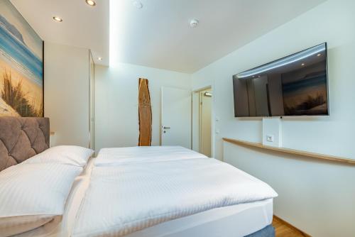 a bedroom with a bed with a tv on the wall at Well-Home Apartments Velden in Velden am Wörthersee