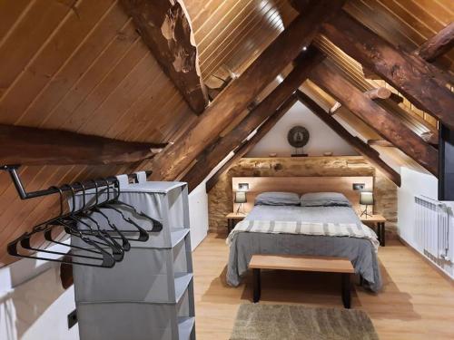 a attic bedroom with a bed and wooden ceilings at El Regueron in Folgoso de la Ribera