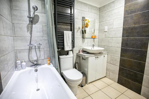 a bathroom with a tub and a toilet and a sink at Oldbrook House, MK City Center, Large Groups. in Milton Keynes