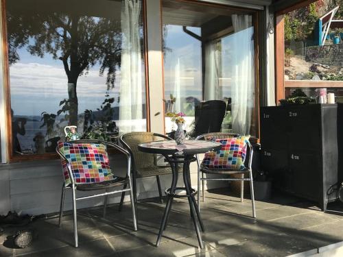 a table and chairs on a porch with a window at Villa med panoramautsikt, stor uteplass og 100 m fra badestrand in Bergen